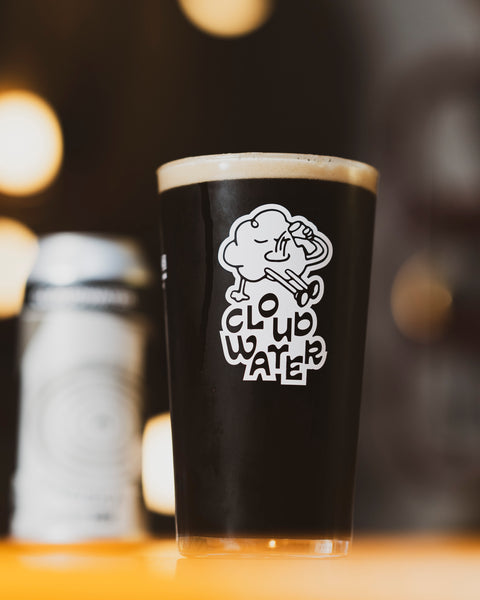 A pint glass with a white 'CLOUDWATER' cartoon logo. The glass is filled with dark, creamy low-alcohol stout, FRESKA. Our first AF stout is topped with a foamy head