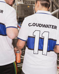 Two people wearing white and blue football shirts one holding a can of helles lager