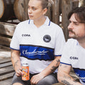Two people wearing Cloudwater Brew Co x COPA Retro Football Shirts sitting next to wooden barrels.