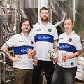 Three of the packaging team including mr jolly in the middle, all wearing Cloudwater Brew Co x COPA Retro Football Shirts in the brewery, enjoying a freshly brewed Cloudwater Helles lager