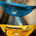 Cloudwater branded bum bags, in teal and mustard yellow