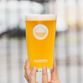 A beautiful golden orange pint of Cloudwater german-style wheat beer held up on a bright background
