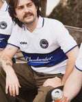 Man wearing a cloudwater blue and white football shirt sitting outside enjoying a can of beer