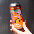 Person holding a bright orange can of Cloudwater Helles beer against a grey background in the sun
