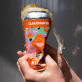 Person crushing a bright orange can of Cloudwater Helles German-Style Beer against a grey background in the sun
