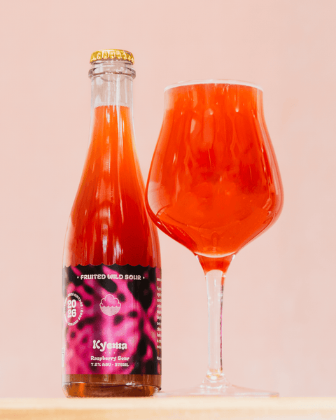 Bottle and glass of Kyema - red raspberry fruited wild sour beer on a light pink background