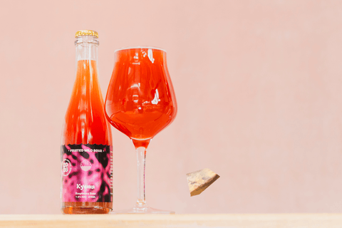 Bottle and glass of Kyema - red raspberry fruited wild sour beer on a light pink background