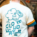 'Cloudy' premium baggy fit tee in Natural Raw being worn by a man. A playful print features on the back of the t-shirt with a cartoony cloud drinking beer whilst reclining