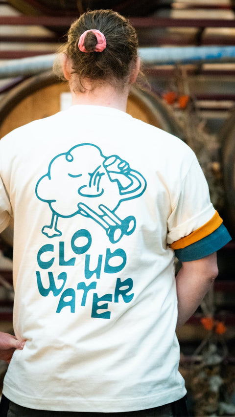 'Cloudy' premium baggy fit tee in Natural Raw being worn by a man. A playful print features on the back of the t-shirt with a cartoony cloud drinking beer whilst reclining