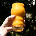 A hand holding a bright orange glass of delicious looking mango sour beer from Cloudwater Brewery. The sun is shining on the glass and it looks unbelievably summery