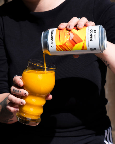 Person pouring Cloudwater Brewery Mango sour beer into a glass